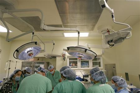 Doctors and nurses assist in the preparation of a patient during a breast implant and skin reduction surgery in Monmouth